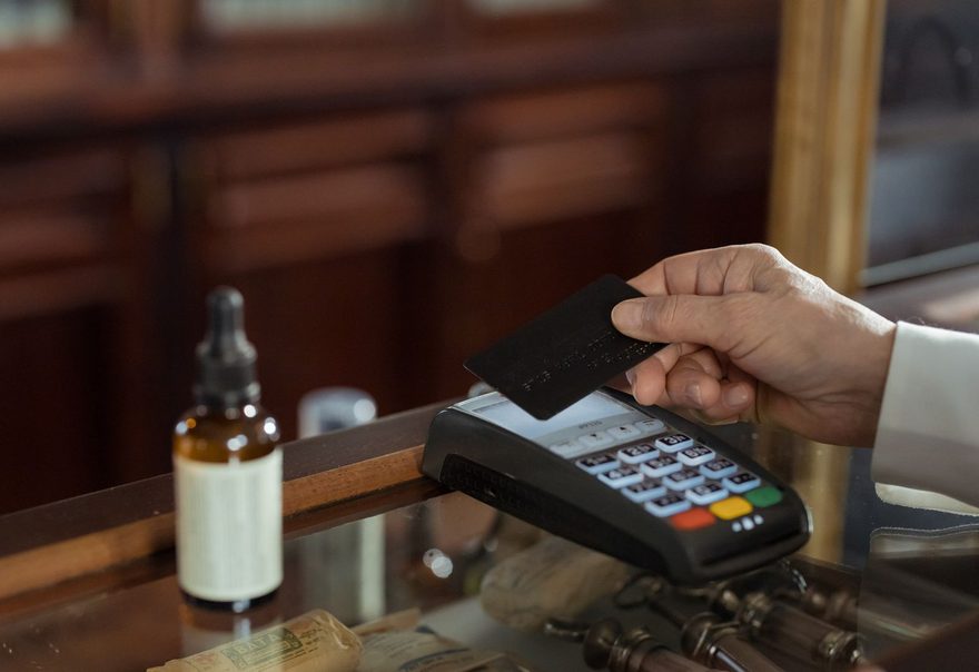 A card being tapped on a countertop terminal at a wooden shop counter