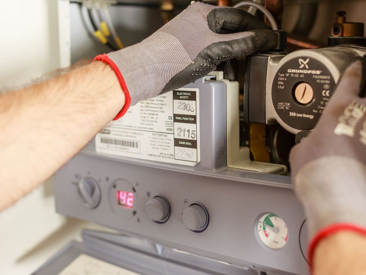 A gloved hand adjusting the controls on a heating system