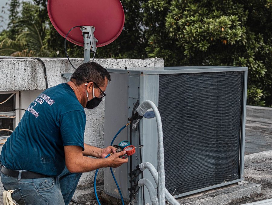 A technician servicing an outdoor air-conditioning unit