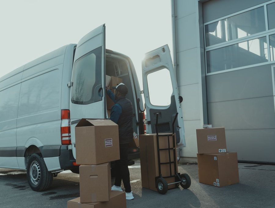 A worker loading boxes into a delivery van outside a warehouse