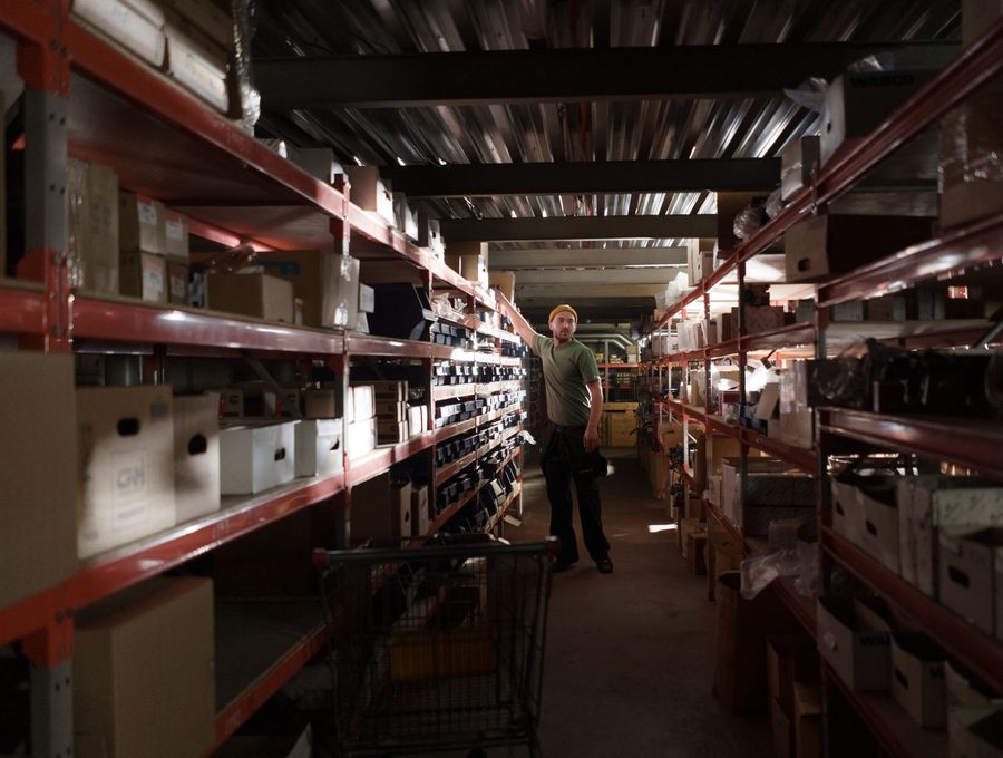 A worker organising stock along a warehouse shelving aisle