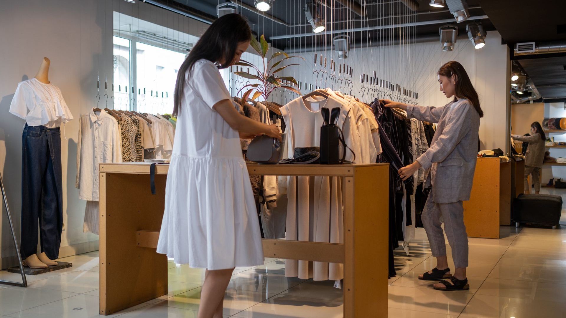Two customers browsing a rail of clothes in a bright modern boutique