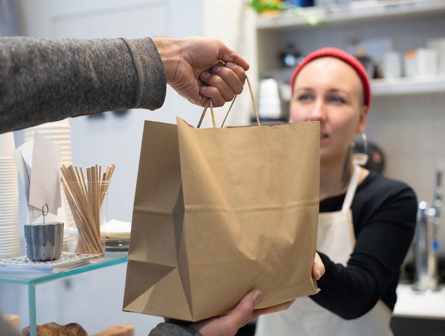 A shop assistant handing a paper bag to a customer