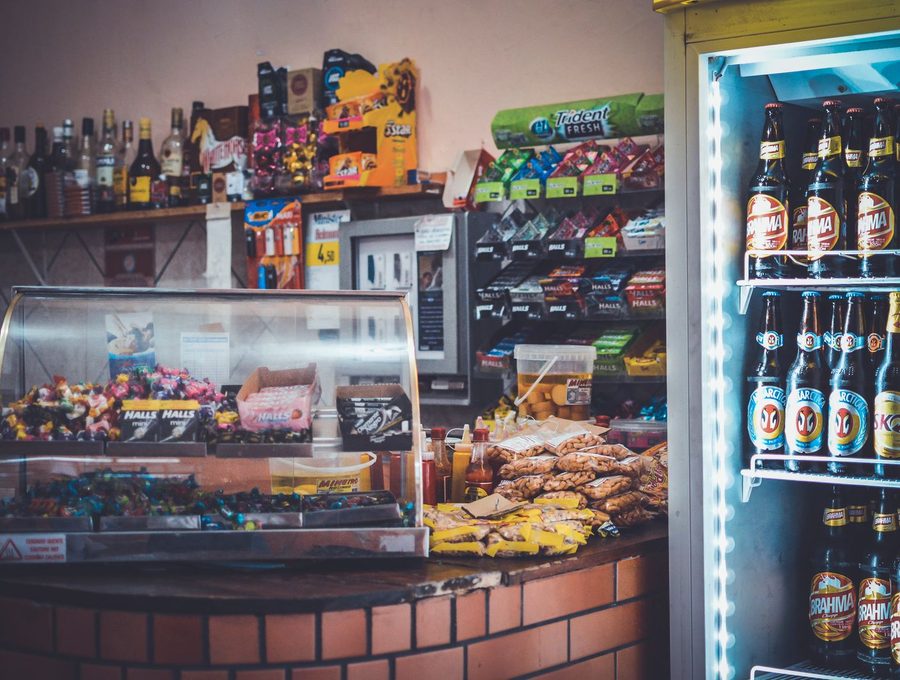 A shop counter with confectionery, a hot case and a drinks fridge