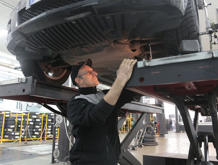 A technician working beneath a car raised on a lift