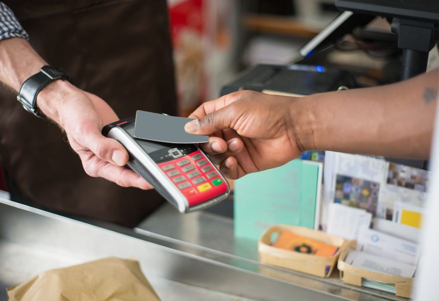 A card being tapped against a countertop payment terminal