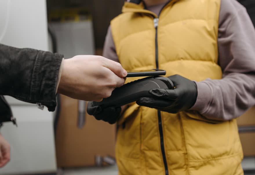 A phone being tapped against a handheld payment terminal