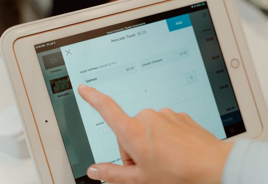 A finger tapping a point-of-sale tablet screen