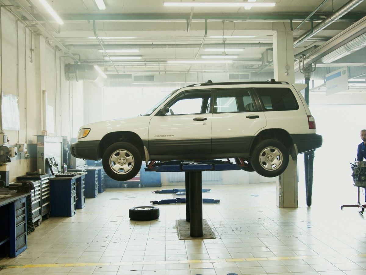 A vehicle raised on a post lift in a wide, clean workshop bay