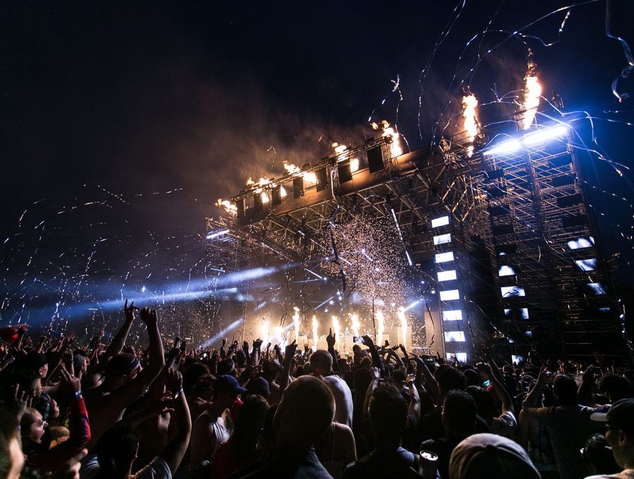 A crowd in front of a lit stage at a night event